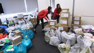 На фото волонтёры Москвы в пункте приёма гуманитарной помощи раскладывают посылки.