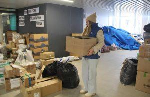 На фото девушка волонтёр из народного фронты разбирает гуманитарную помощь по коробкам.