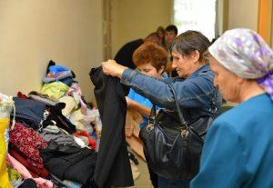 На фото люди оказавшиеся в сложной ситуации в жизни мерят одежду для себя и выбирают для членов своих семей.