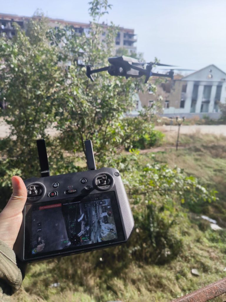 На фото оператор БПЛА управляет дроном на фронте через пульт управления квадрокоптером.