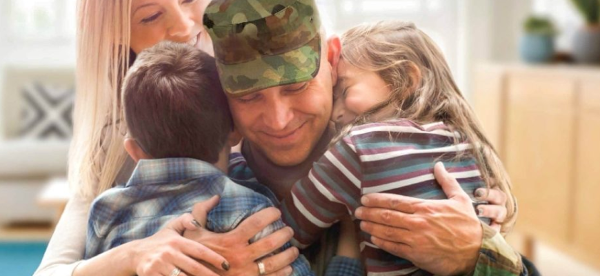На фото военный солдат контрактник прощается с семьёй перед уходом на фронт СВО по защите Отечества.